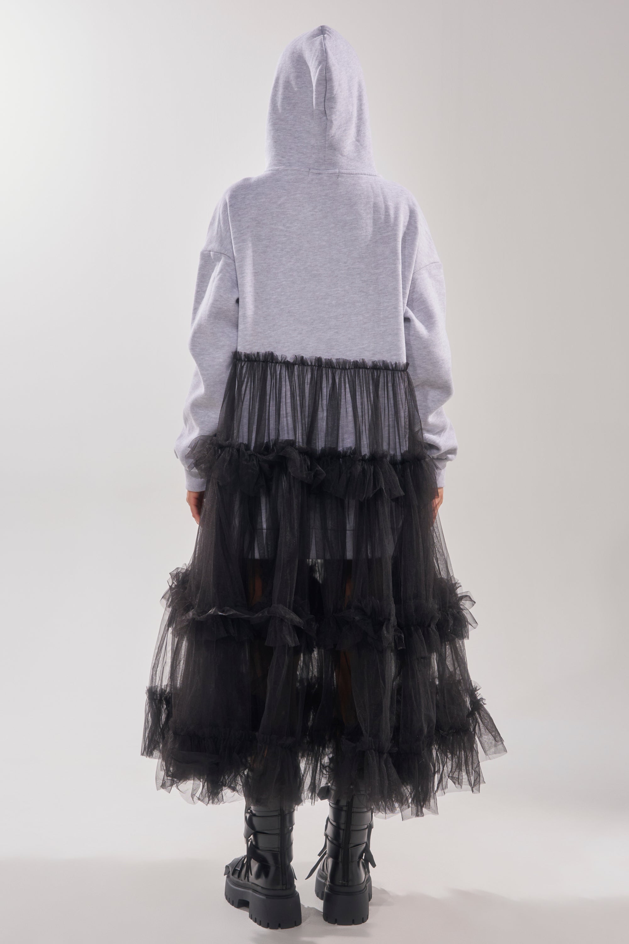 A person faces away, wearing the DO SOMETHING CRAZY SWEATSHIRT DRESS in light gray with a long sheer black tulle skirt and black combat boots, set against a plain light background.