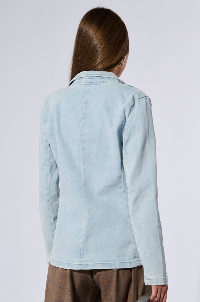 A woman in a relaxed fit, light blue ROBYN DENIM BLAZER exudes business chic elegance.