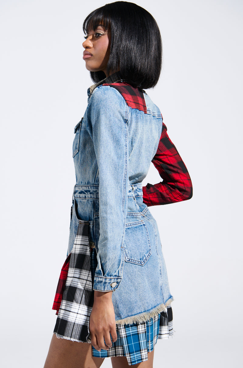 A person wears the edgy PATCHWORK PLAID DENIM MINI DRESS: a denim jacket and plaid skirt combo with red, black, and blue patchwork. A fringed hem adds punk flair as they stand in profile against a plain backdrop.
