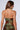 A person with long brown hair is seen from the back, wearing the IN THE DARK HALTER TOP—a green halter neck adorned with velvet floral accents. The top features a metallic back zipper closure running down the center, all against a plain, light-colored background.