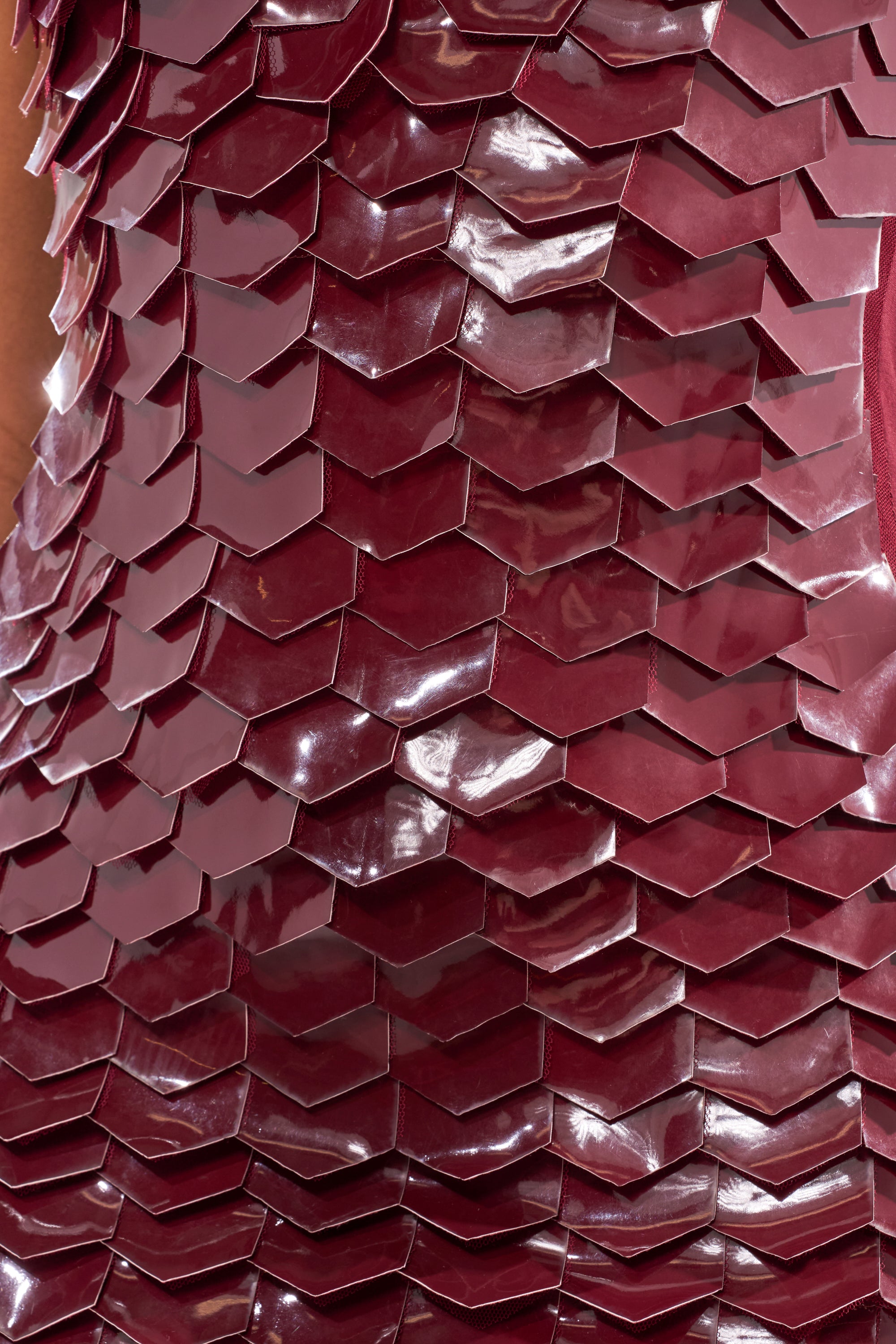 The CRAZY IN LOVE SCALE MINI DRESS showcases shiny, burgundy, scale-like pieces in overlapping rows, creating a textured and eye-catching reflective effect.