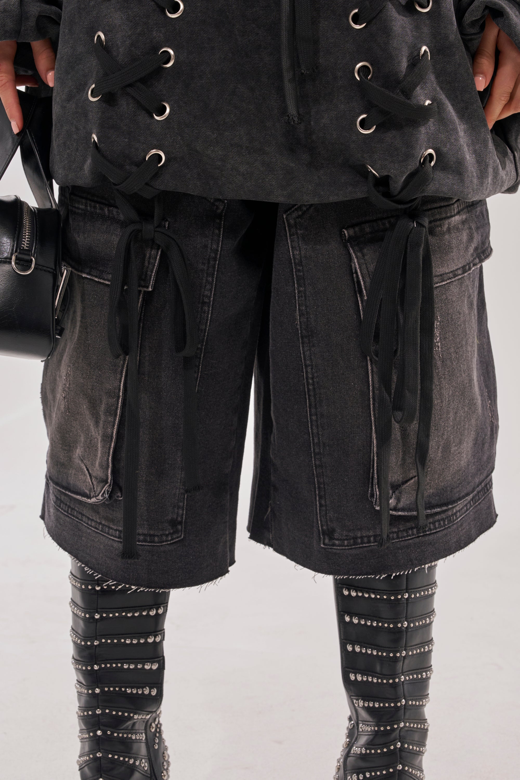 Wearing the LACED UP FOR GOOD MINI DRESS, paired with charcoal gray lace-up boots with silver studs and a black handbag. This edgy, modern look features bold lace-up detailing and striking metallic accents.