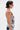 A person with short dark hair and sunglasses wears the OUT OF MY LEAGUE DENIM HALTER TOP with graphic prints and matching pants, showing a red paint-like design on their shoulder against a plain white background.