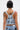 Person with short dark hair and bleached streaks, seen from behind, wears the OUT OF MY LEAGUE DENIM HALTER TOP with arm tattoos and a necklace.