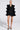 In a minimalist white setting, a person poses confidently in the chic LIVING OVER THE TOP RUFFLE SLEEVE BLAZER MINI DRESS, showcasing its luxury with gold buttons. The ensemble is completed with elegant black high heels adorned with gold accents, highlighting its sophisticated allure.