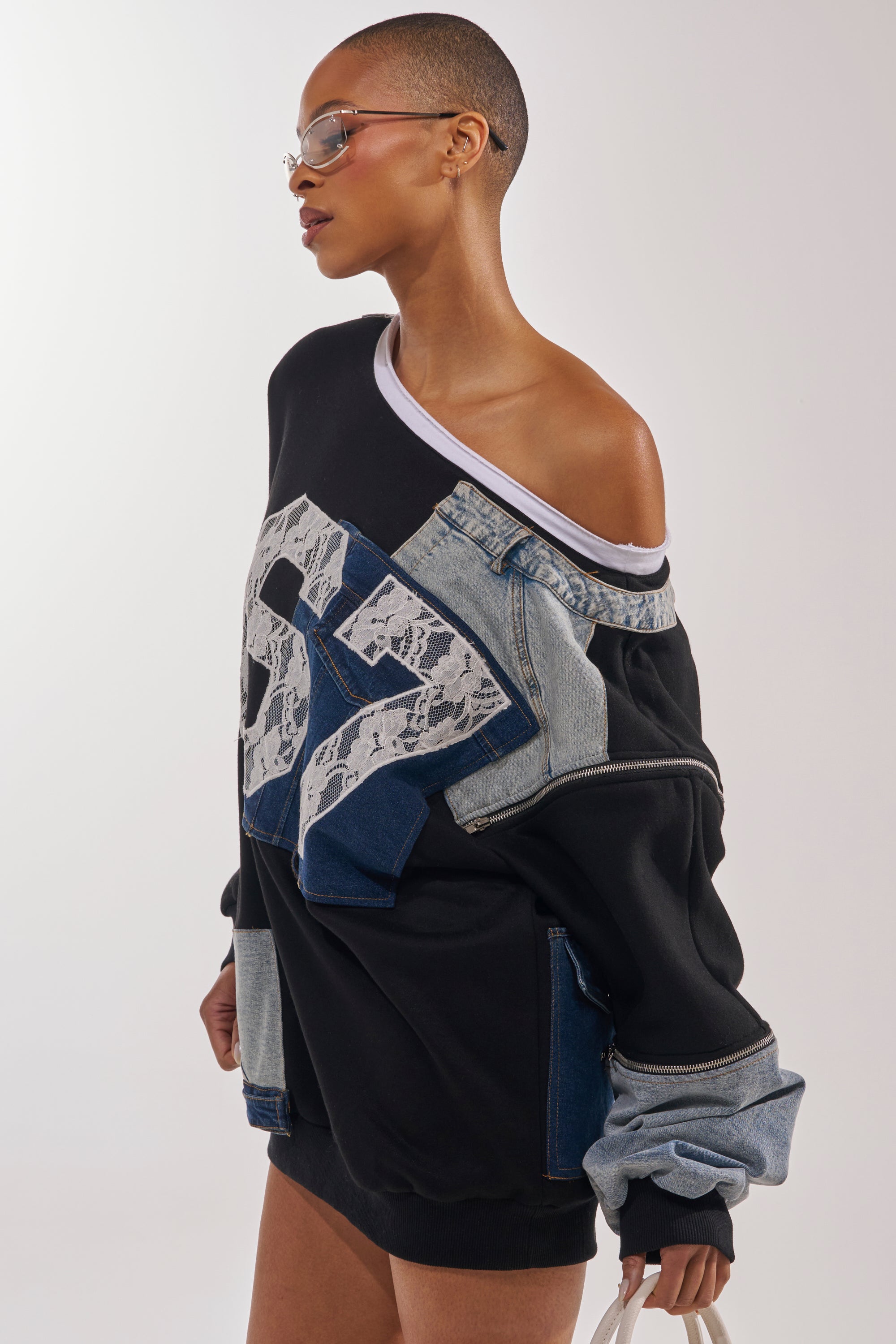 A person with a shaved head wears sunglasses and the DREAM TEAM FRENCH TERRY MINI DRESS, featuring denim and lace patches, posing confidently against a plain background. 3