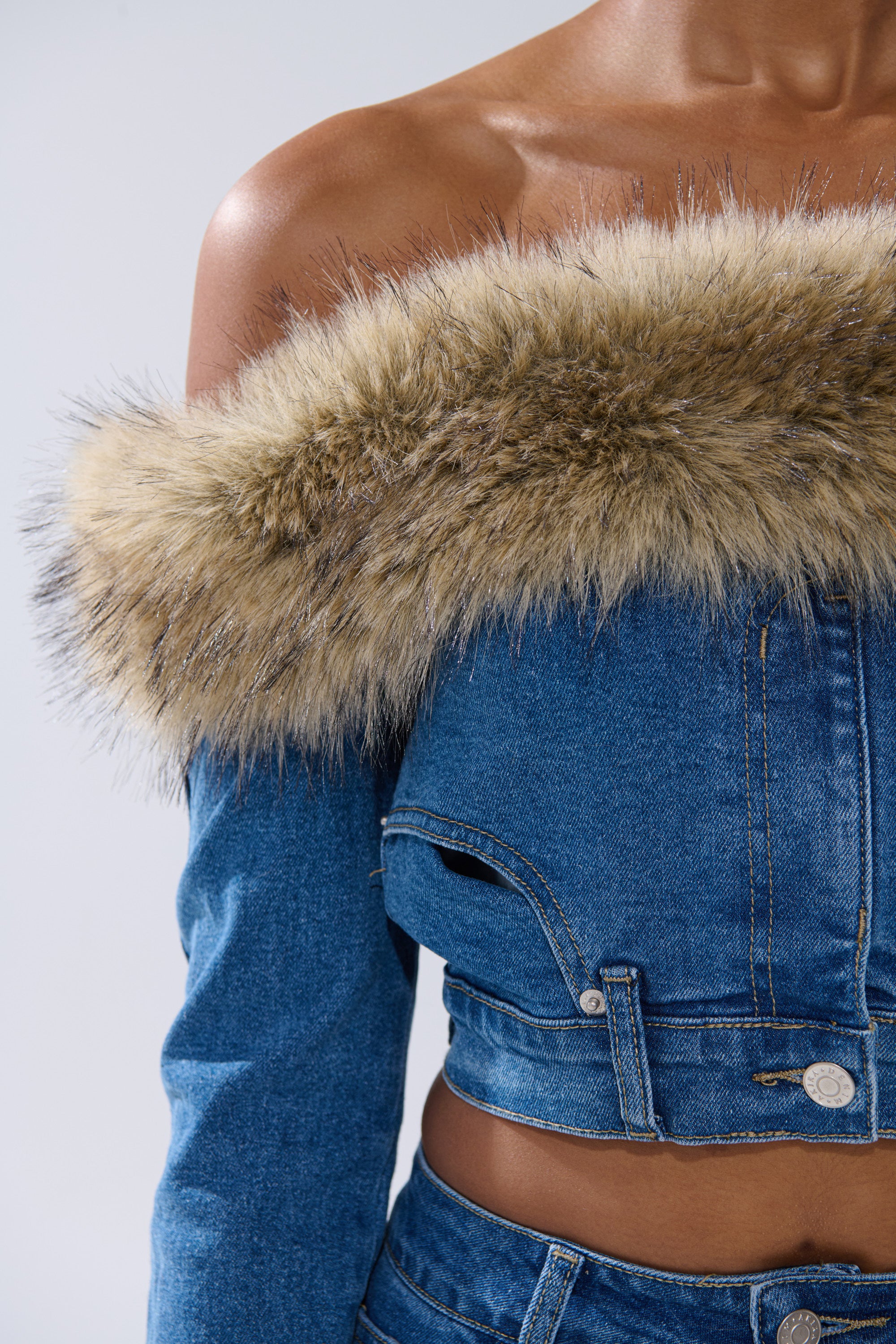 A person wears the FLUFFY OFF THE SHOULDER LONG SLEEVE TOP in blue denim, styled with a wide faux fur trim on the neckline and sleeves. The photo is cropped at the shoulders and waist.