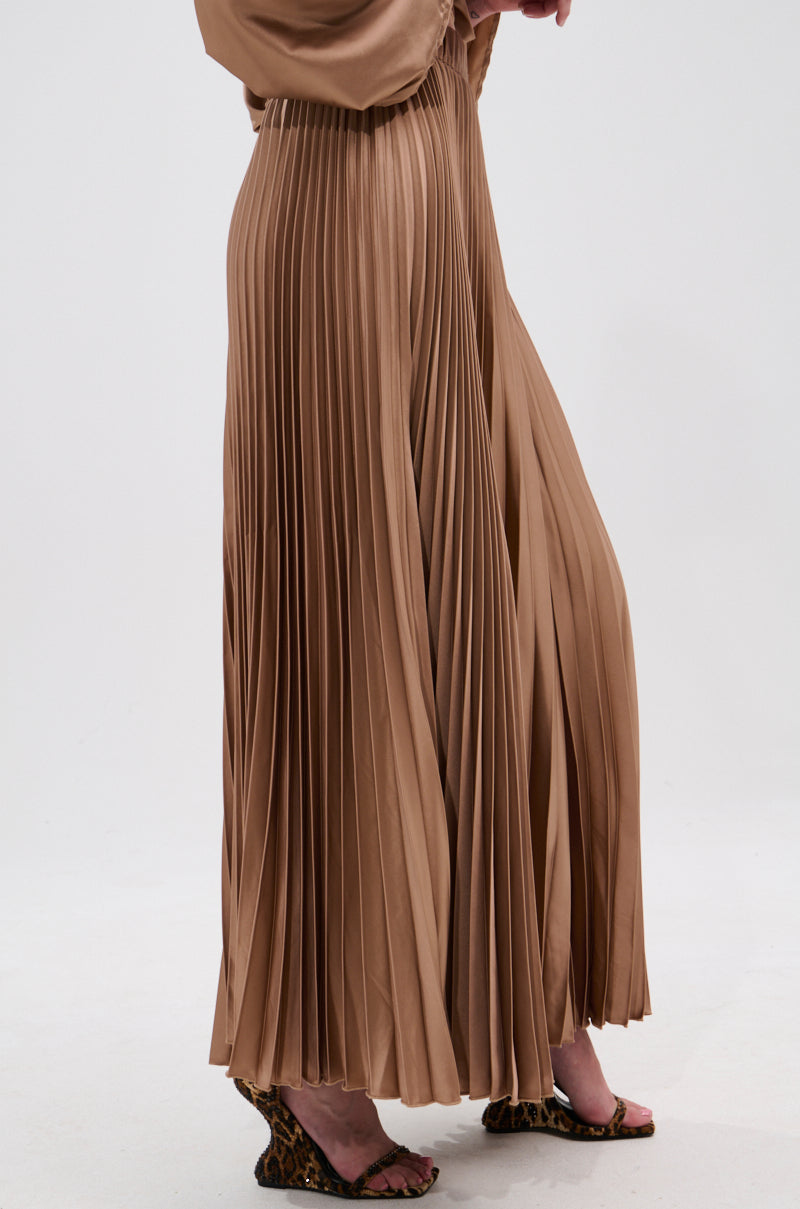 A person wearing the MILLIE MOCHA MOUSSE SATIN MAXI SKIRT with accordion pleats and leopard print heeled sandals stands against a plain white background. Only their lower body is visible. 4