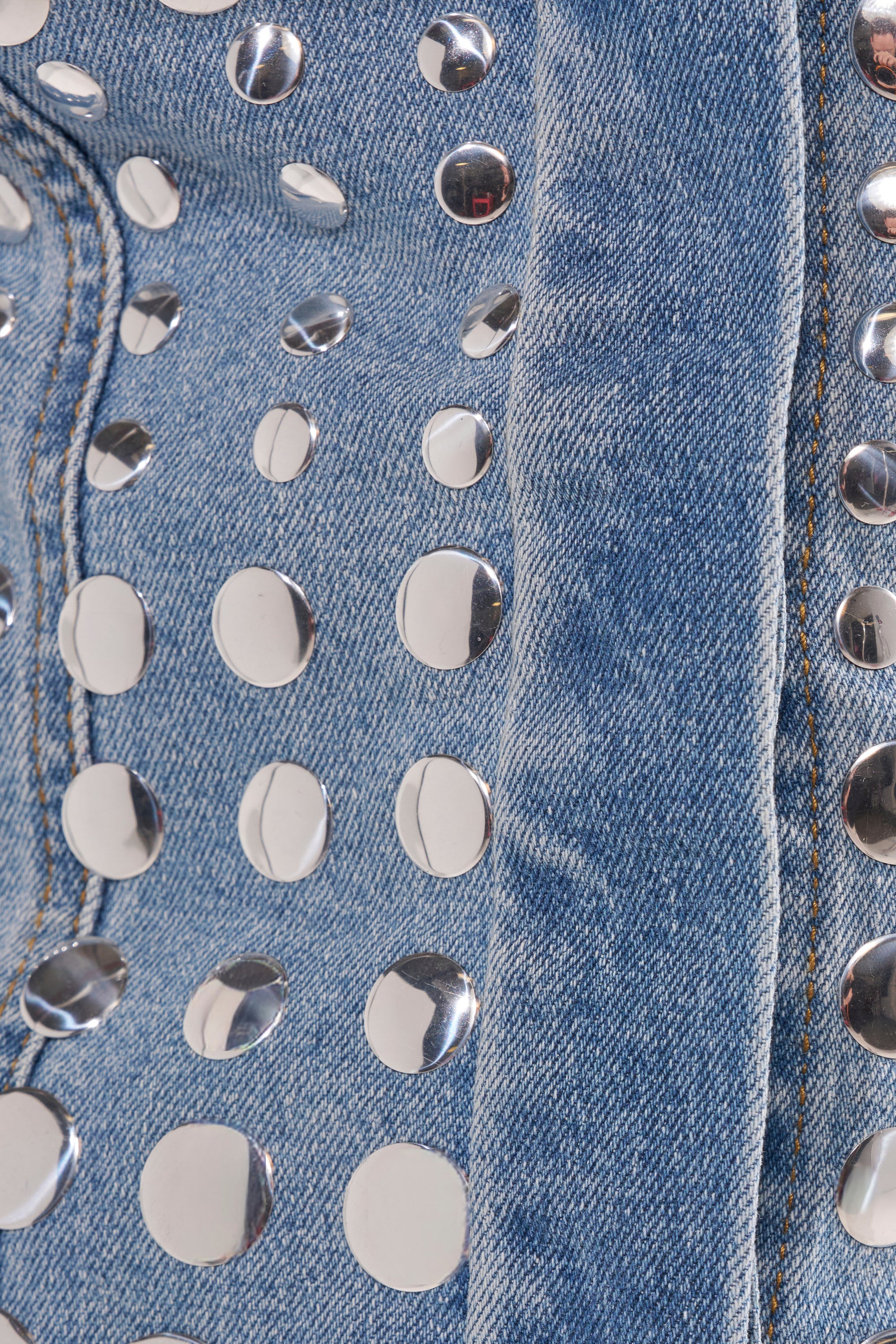 Close-up of the STUDS EVERYWHERE BUTTON DOWN: blue denim fabric adorned with shiny silver studs arranged in a scattered pattern. 9