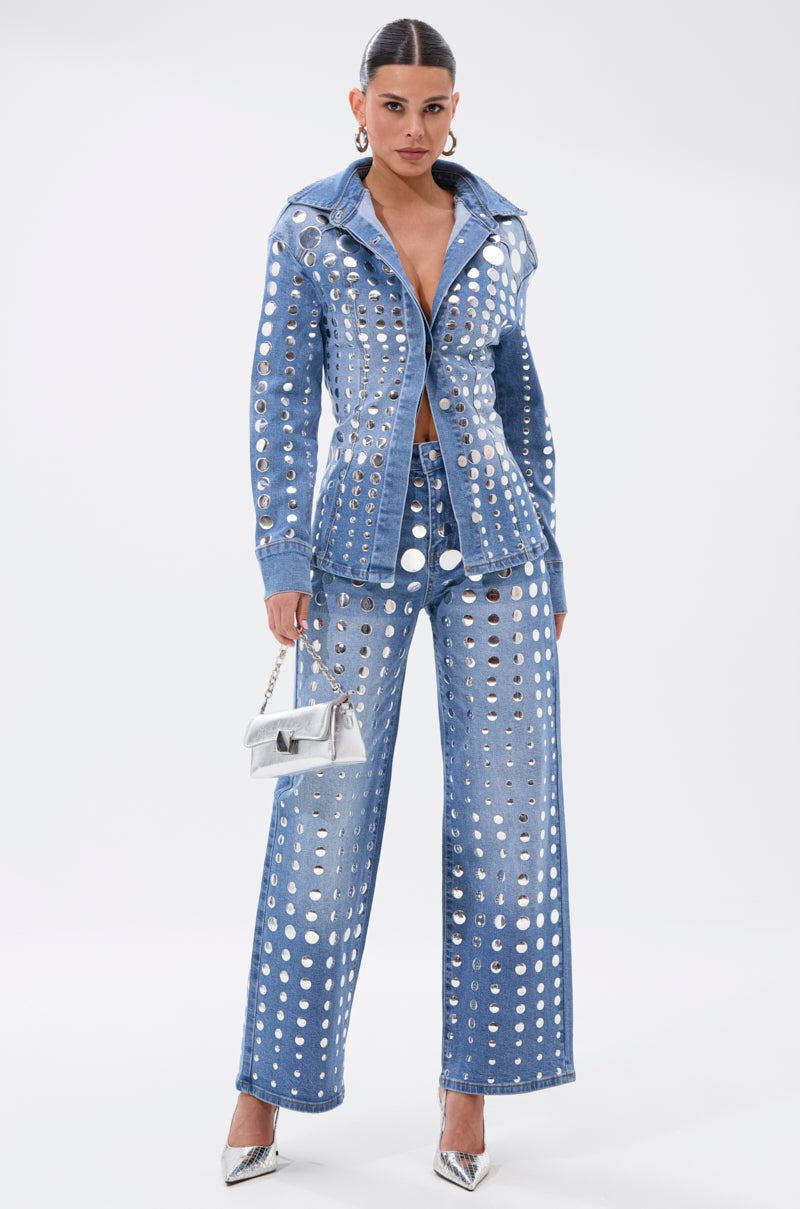 Wearing the STUDS EVERYWHERE BUTTON DOWN denim top and wide-leg pants with silver cutouts, plus a small silver handbag and silver high heels, a person stands against a plain white background.
