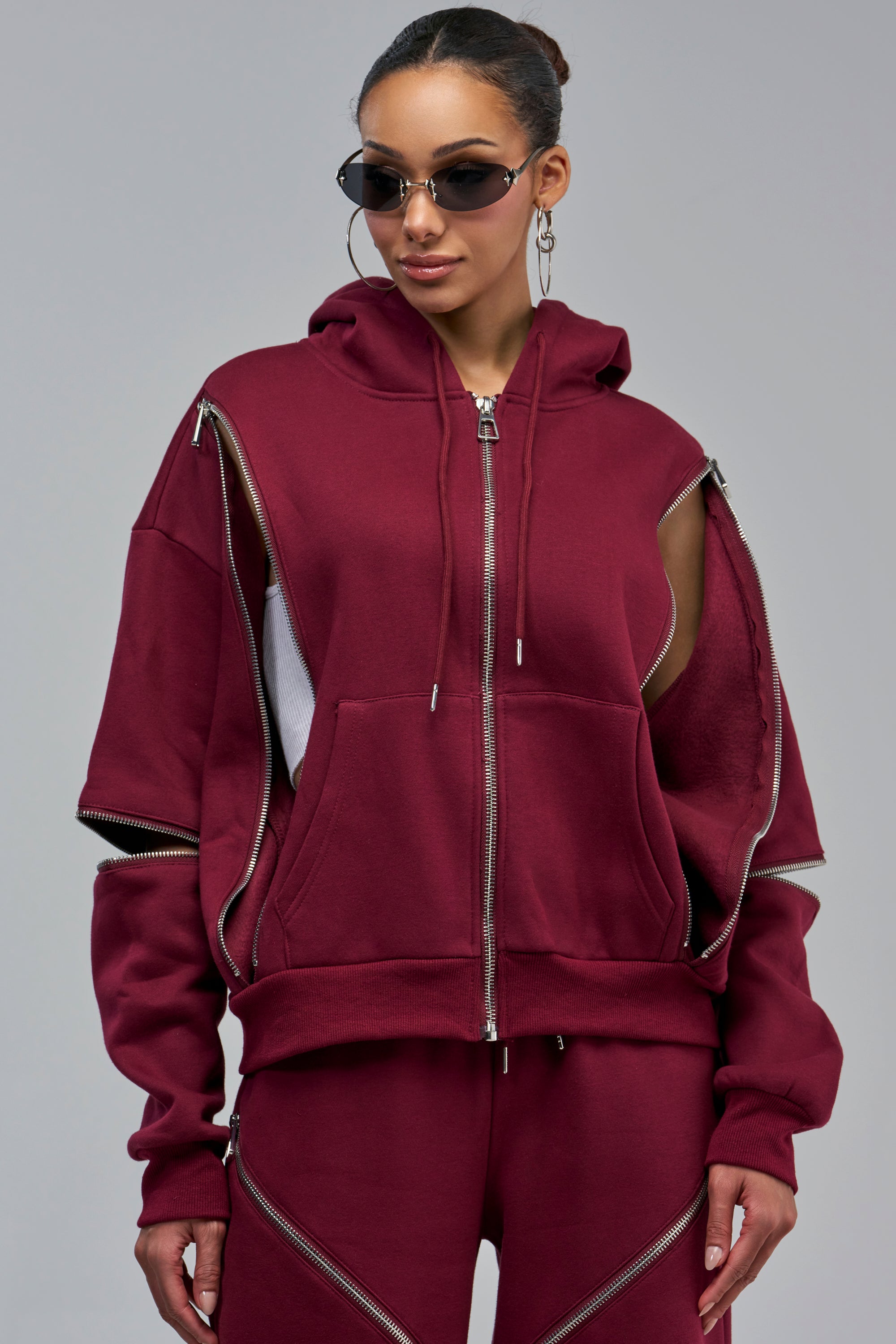 CALI MULTI ZIPPER HOODED SWEATSHIRT IN BURGUNDY with a full-length front zipper and side zipper detail at the arms that creates cutouts.