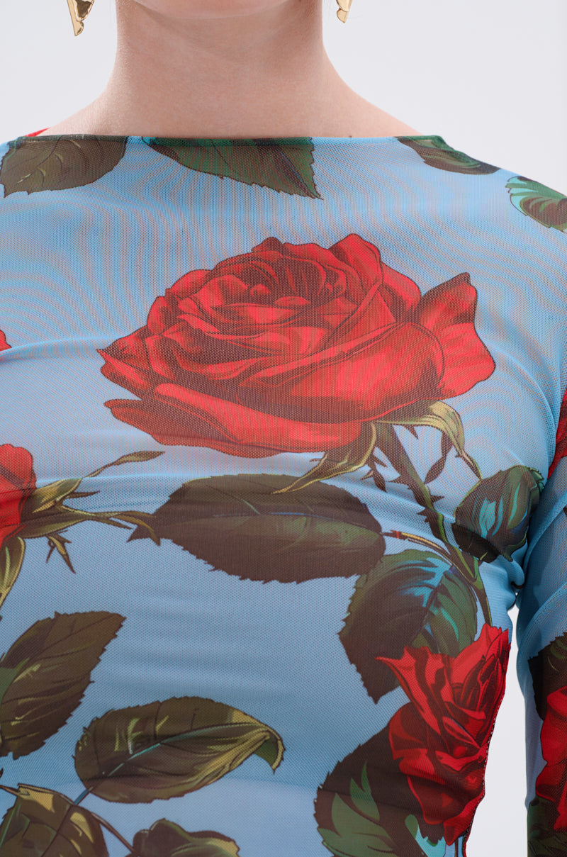 A close-up shows a person in the DOZEN ROSES MESH TOP, with sheer mesh fabric and striking red rose and green leaf graphics. Only their lower face, neck, shoulders, and gold geometric earrings are visible.