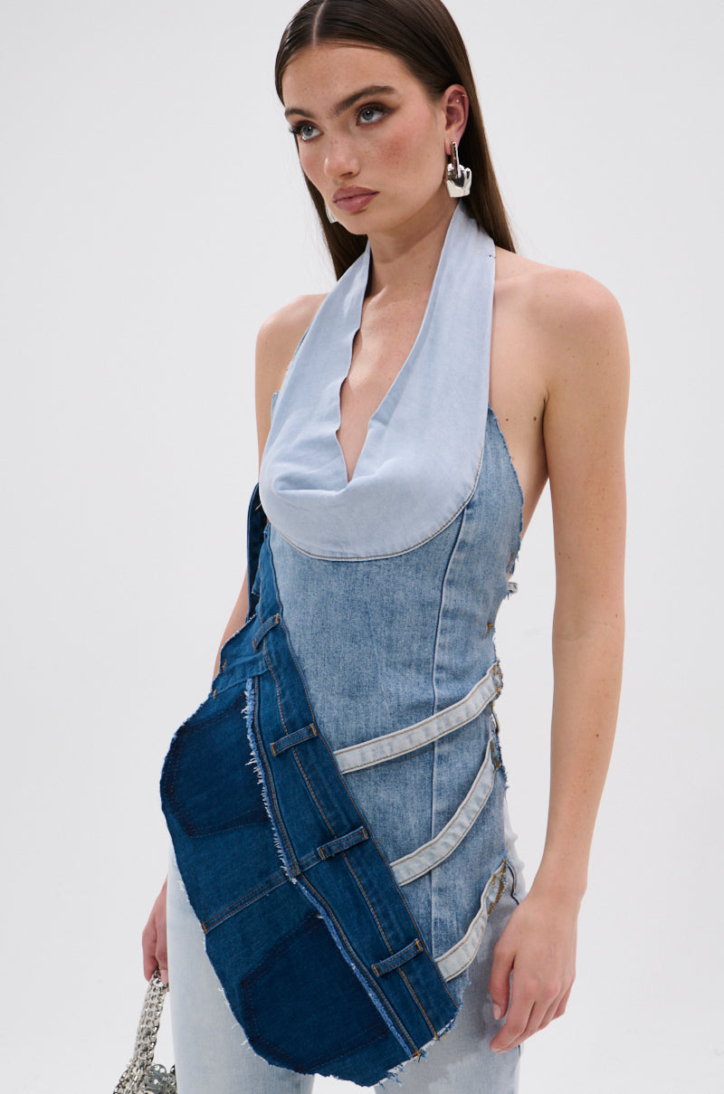 A woman with long brown hair wears the PATCHED UP COWL NECK DENIM HALTER TOP with layered denim, a halter neckline, and buckle details, standing against a plain white background. 0