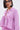 A person with straight, shoulder-length dark hair, black-rimmed glasses, and silver hoop earrings is wearing the TAKE ME TO IBIZA TIE FRONT TOP—a pink, long-sleeve blouse with black and white vertical stripes and a collar.