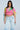 A woman wearing the LOVE LOVE LOVE BLOUSE, yellow sunglasses, and light blue jeans stands facing forward with a neutral expression against a light gray background.