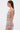 Woman with long straight brown hair wears the TAKE ME TO MIAMI HALTER TOP and matching psychedelic crochet skirt, standing in profile against a plain white background for a bold, retro-inspired look.