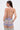 A woman with long brown hair is seen from the back wearing the TAKE ME TO MIAMI HALTER TOP, tied with thin straps, and pastel wavy-patterned pants against a plain white background for a retro-inspired look.