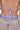 Close-up of a person’s back wearing the TAKE ME TO MIAMI HALTER TOP, showcasing a retro pastel crochet pattern with wavy designs and purple tie strings, paired with matching colorful crochet bottoms.