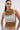 A woman with long dark hair in a ponytail wears futuristic clear sunglasses, the MOST WANTED TANK with a dip-dyed ribbed cotton-blend design, and light blue jeans featuring large metallic eyelets.
