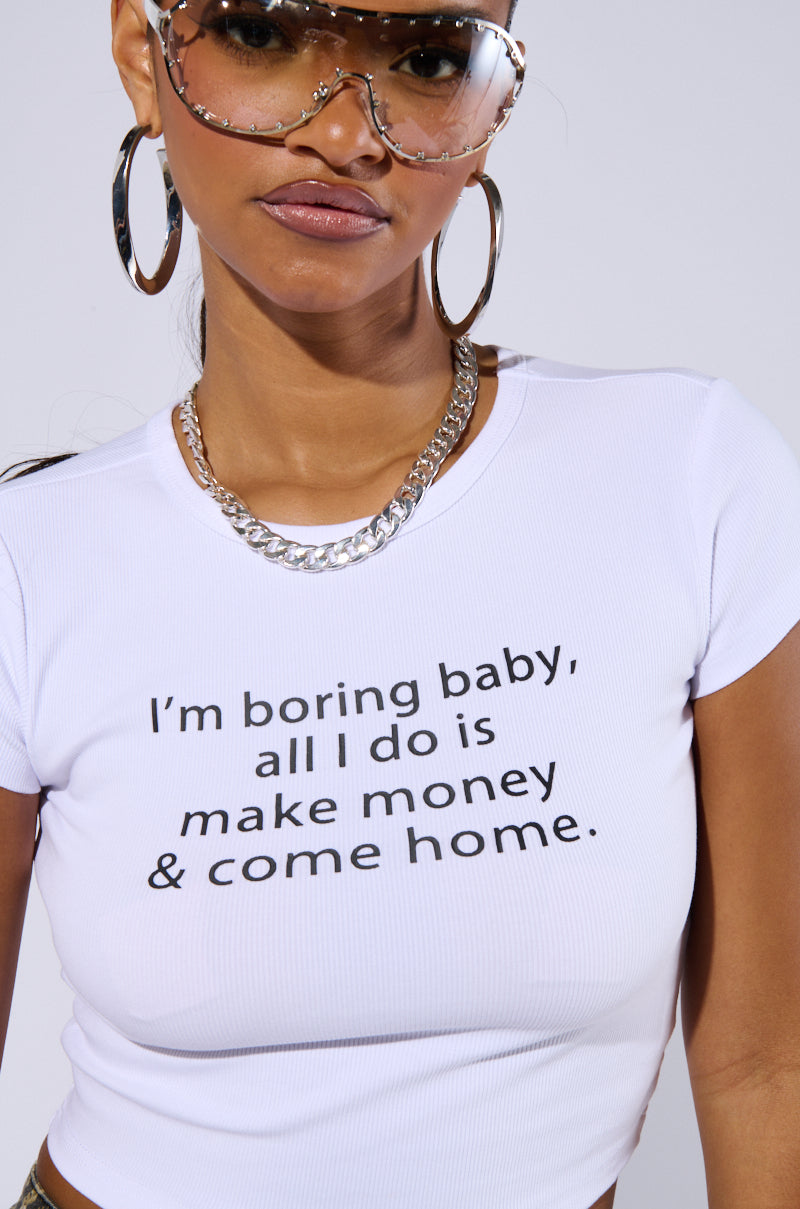 A woman wearing the ALL I DO IS MAKE MONEY GRAPHIC BABY TEE featuring the text "I'm boring baby, all I do is make money & come home," accessorized with large hoop earrings, a chunky silver chain necklace, and fashionable wraparound glasses. Her confident expression exudes rich girl vibes.