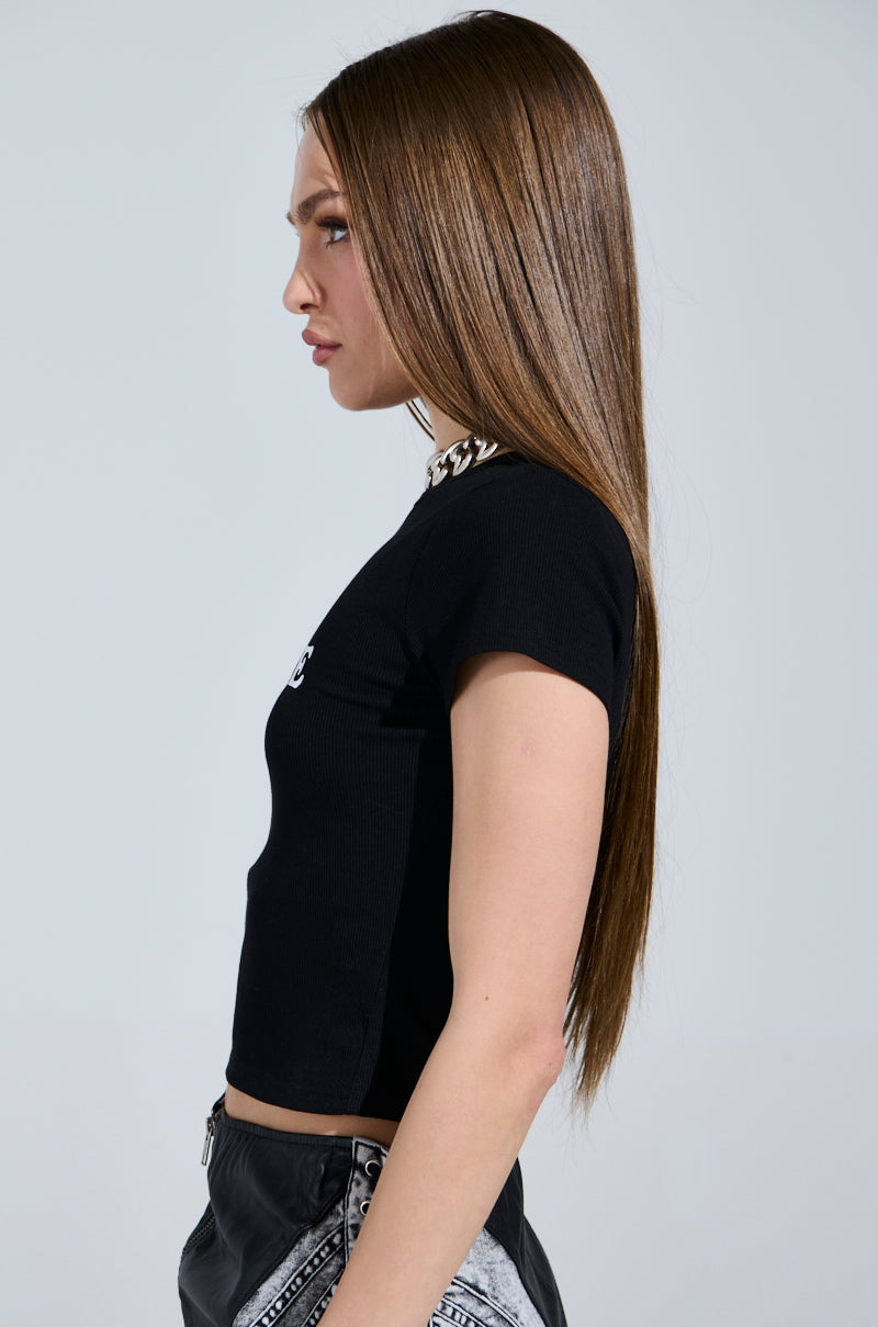 A person with long, straight hair is wearing the FUTURE MILF BABY TEE in black and patterned pants, standing sideways facing left against a plain background. 2