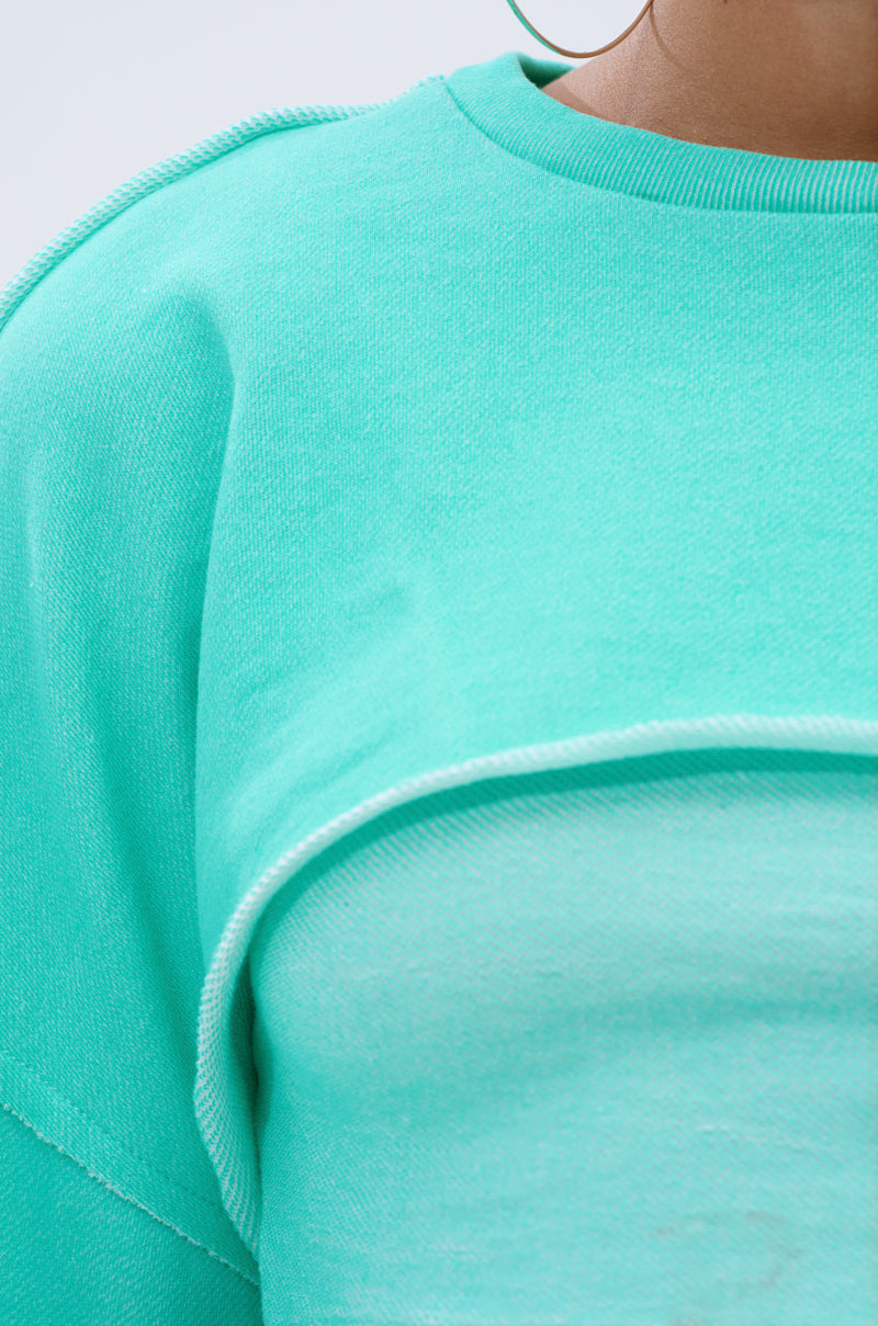 A close-up of a cozy blue loungewear top, styled like the ISSA DOUBLE LAYER CROP SWEATSHIRT IN TIFFANY. 8