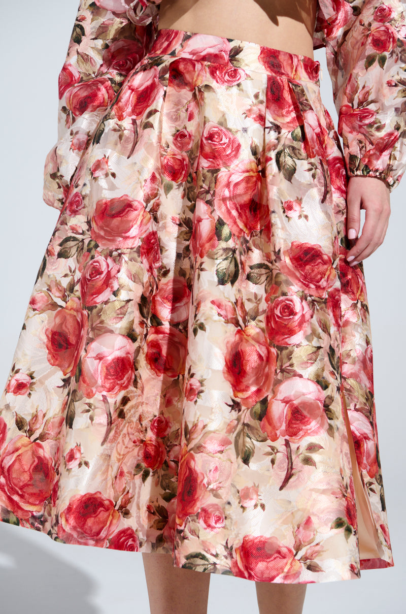 A person is wearing a vintage-inspired ensemble with the DANCE WITH ME FLORAL MIDI SKIRT and blouse, showcasing vibrant red and pink roses on a light background, captured from shoulders to knees.
