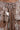 Close-up of a shiny, metallic cargo skirt in bronze. The ALL I NEED METALLIC MAXI CARGO SKIRT features a high-rise fit with a drawstring waist and large pockets. Its flowing design and metallic fabric reflect light for a glossy effect.