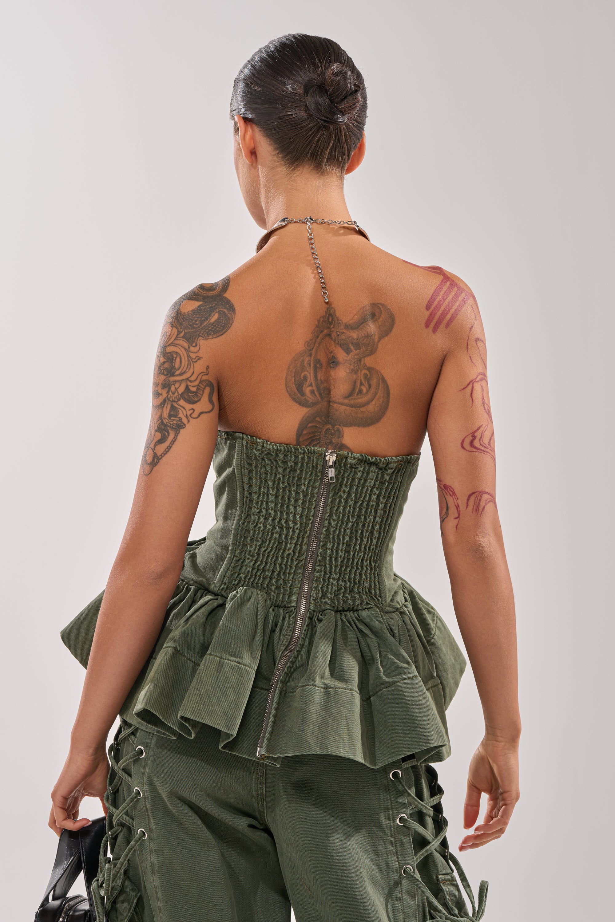 A woman with tattoos on her back wears the KARA DENIM CORSET, featuring an olive wash and a sweetheart neckline. 4