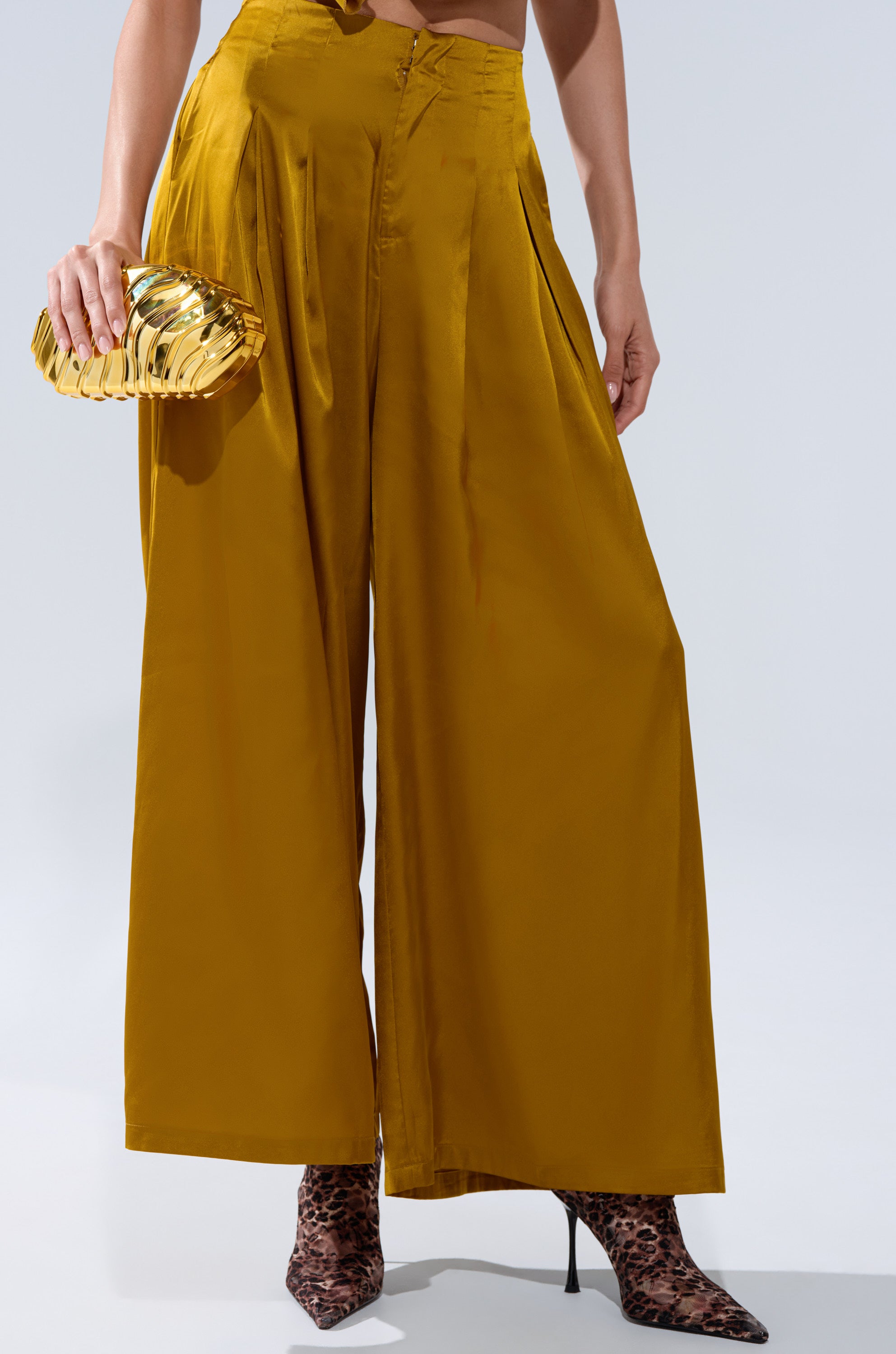 Wearing the COCKTAIL HOUR WIDE-LEG PANT IN MUSTARD with a high-rise waistband, metallic gold clutch, and leopard print heeled boots. Upper body cropped out of the image.