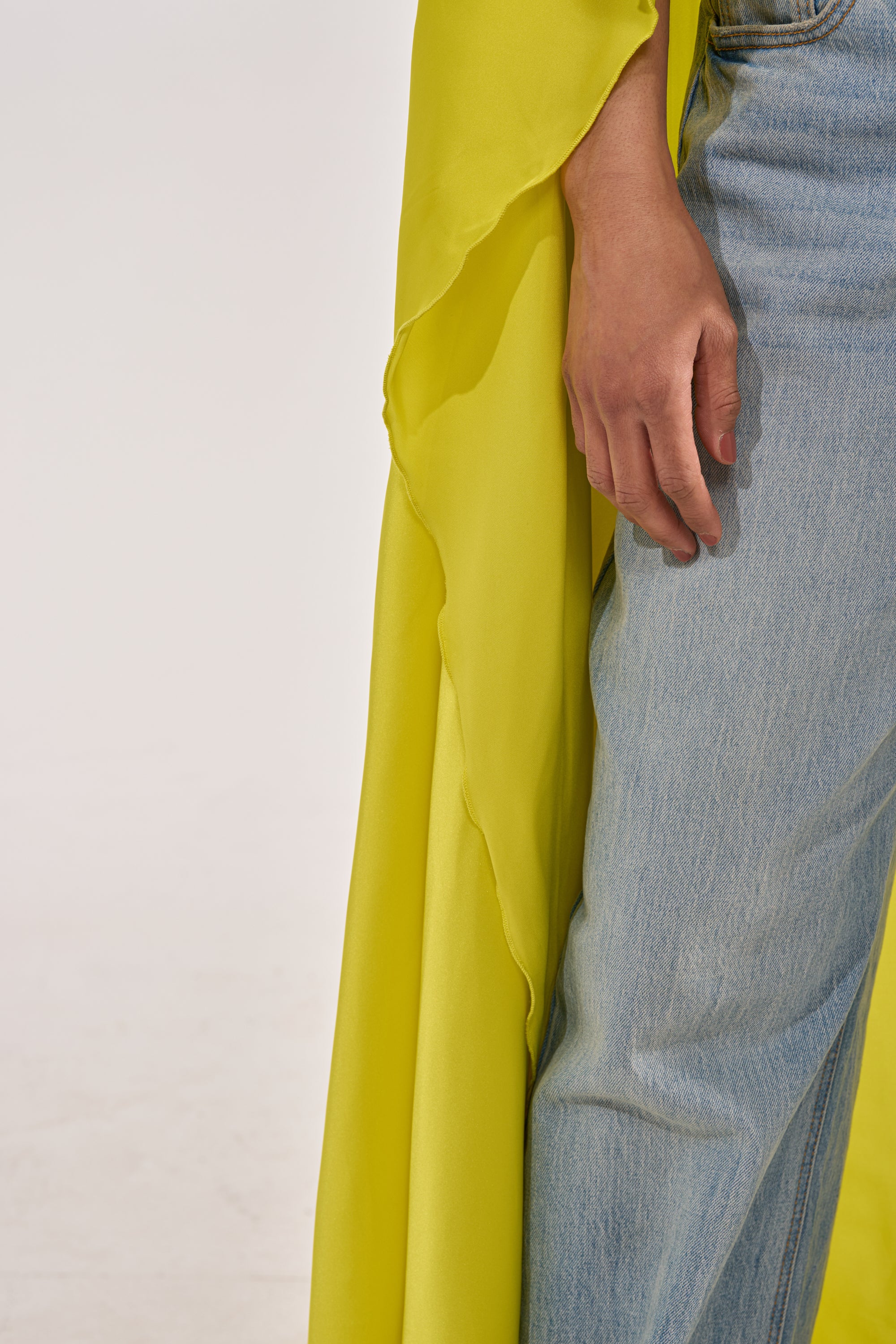 A person wearing the SO CHIC CAPE BLOUSE IN YELLOW paired with light blue jeans, standing against a plain background with their hand resting by their side. 3