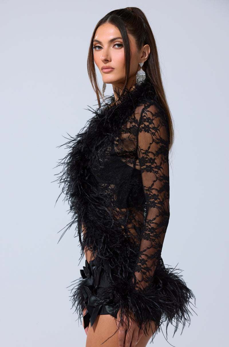 A woman with long brown hair models the SEXY LACE BLOUSE, featuring feather trim and paired with large silver earrings, posing confidently against a plain light background. 4