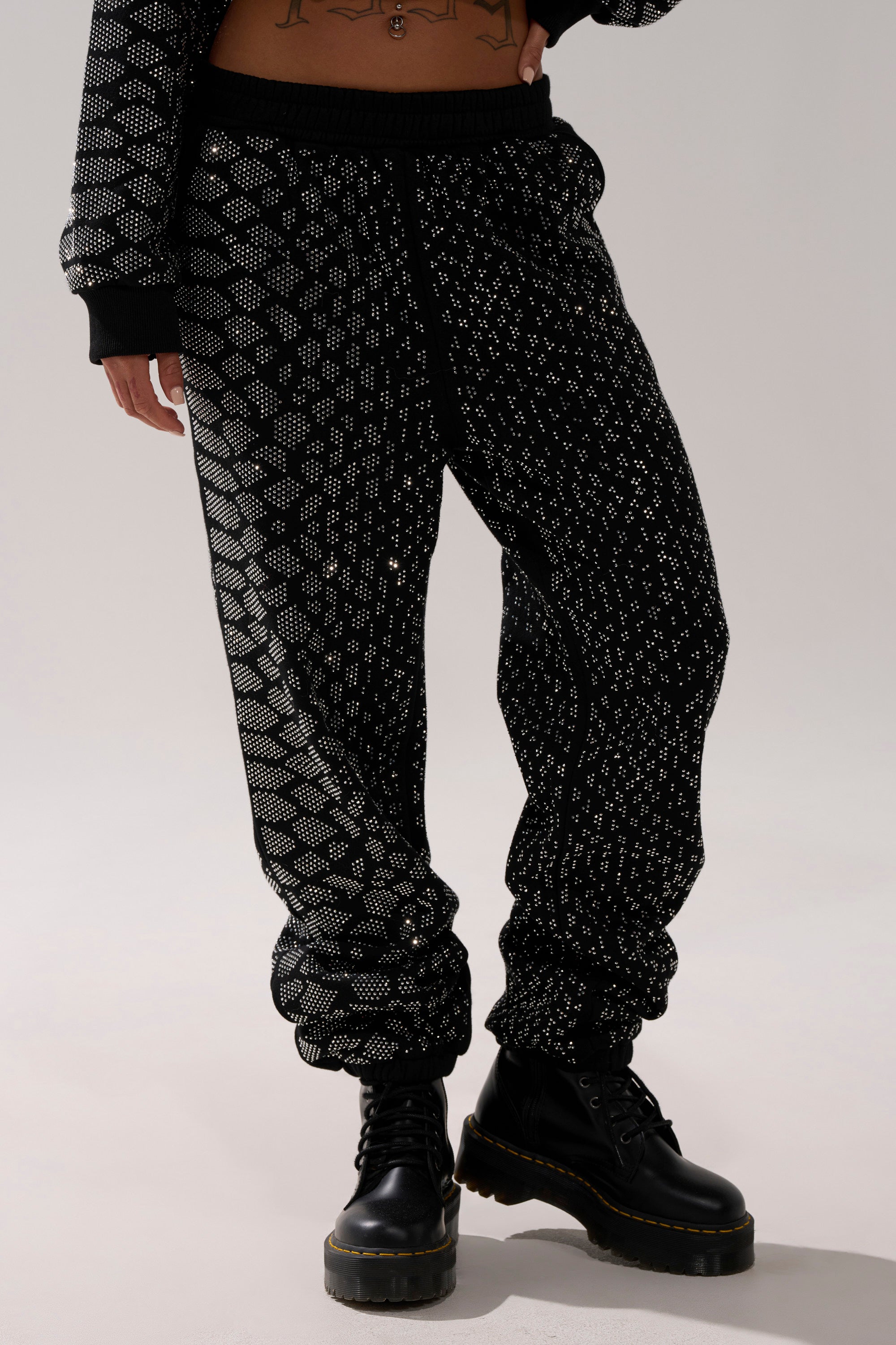 A person wearing the SNEAKY LITTLE SNAKE WIDE LEG JOGGER and black platform lace-up boots stands with legs slightly apart against a plain background, showing only the lower half of their body.