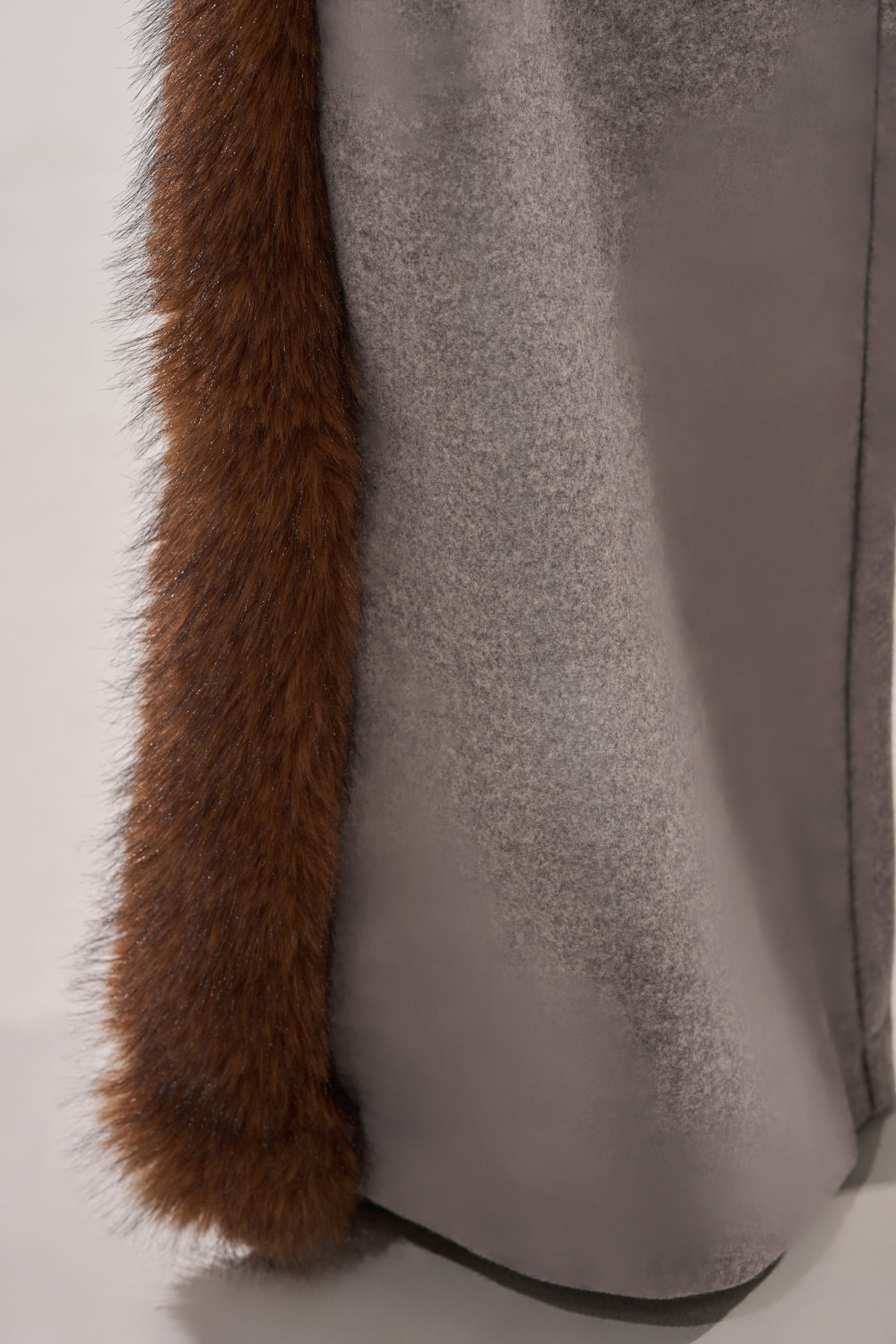 A close-up shows the hem of a gray coat with thick brown fur trim, evoking the luxurious detail of the HALLE FUR TRIM WIDE LEG PANT. The neutral background is out of focus.
