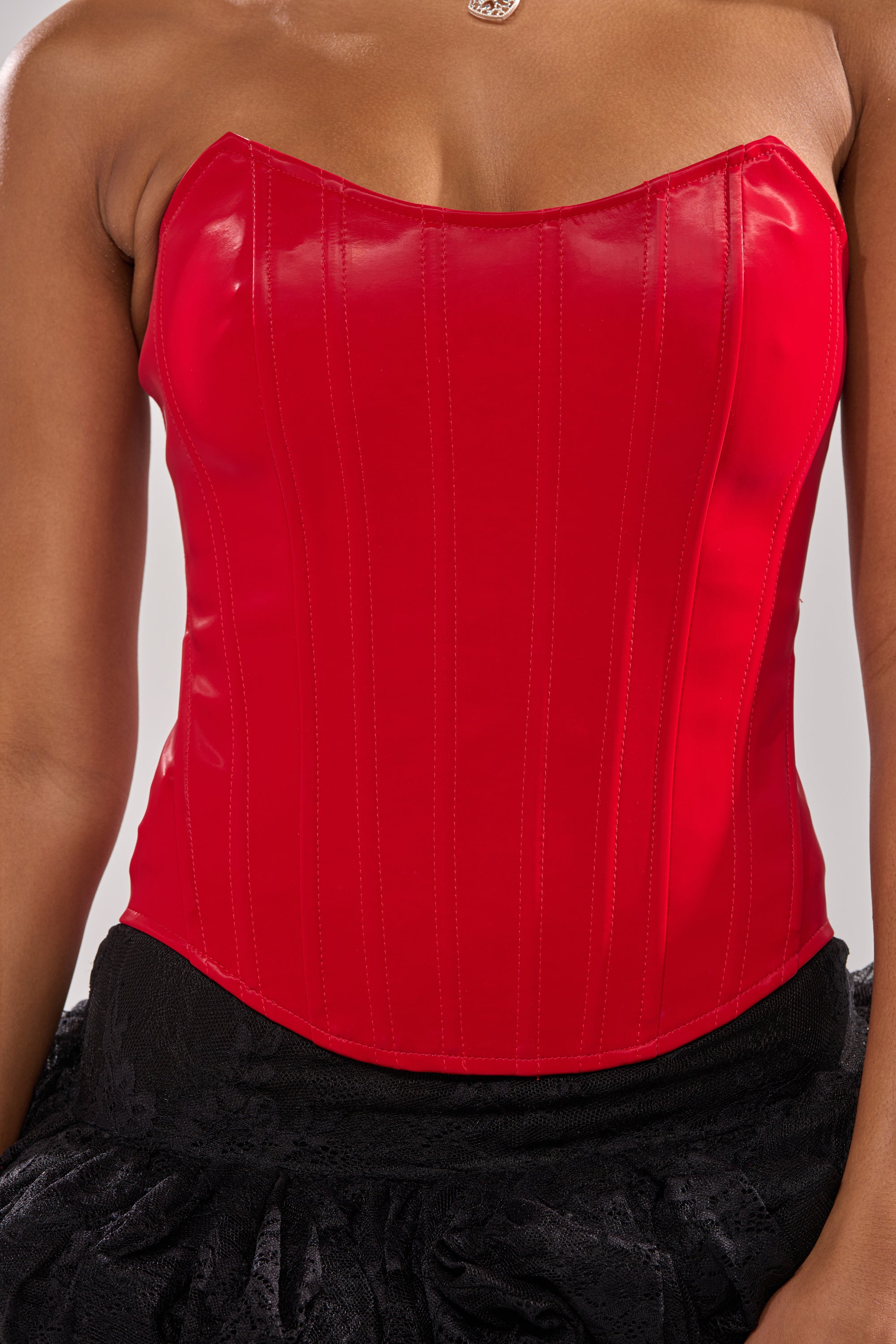 A person wears the STAY OUT MY WAY CORSET IN RED with vertical stitching, paired with a textured black skirt. Only the upper torso is visible. 5