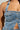 Close-up of a person wearing the JOLIE RHINESTONE EMBELLISHED DENIM CORSET, showcasing its silver buttons, pocket adorned with shiny studs, rhinestone embellishments, frayed edges, halter straps, distressed detailing, and intricately cropped silhouette.