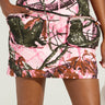 Someone is wearing the "WEAR IT TWO WAYS MINI SKIRT OR DRESS," featuring a nature-inspired, colorful pattern reminiscent of pink camouflage with pink, green, and brown leaves. The skirt has large front pockets against an off-white background.