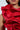 Wearing the MISS FASHIONISTA Sleeveless Ruffle Peplum Blouse in Red, a woman captivates attention with its vivid hue and subtle shine. The eye-catching intricate ruffles complement her features, highlighting her lips and part of her face.