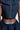 The individual is styled in an AKIRA Label MISS FASHIONISTA SLEEVELESS BLOUSE with a zipper, paired with a ruffled denim skirt. The outfit features a chic cutout detail that reveals parts of the waist and back against a plain, light-colored background.