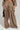 The ensemble highlights the TALK ABOUT ME TROUSER by AKIRA Label, characterized by flowy brown pants with a wide-leg silhouette and large cargo pockets. The high-rise design of these trousers enhances the outfit's relaxed and casual flair, complemented perfectly by a matching top. A glossy black handbag finalizes the look with ease.