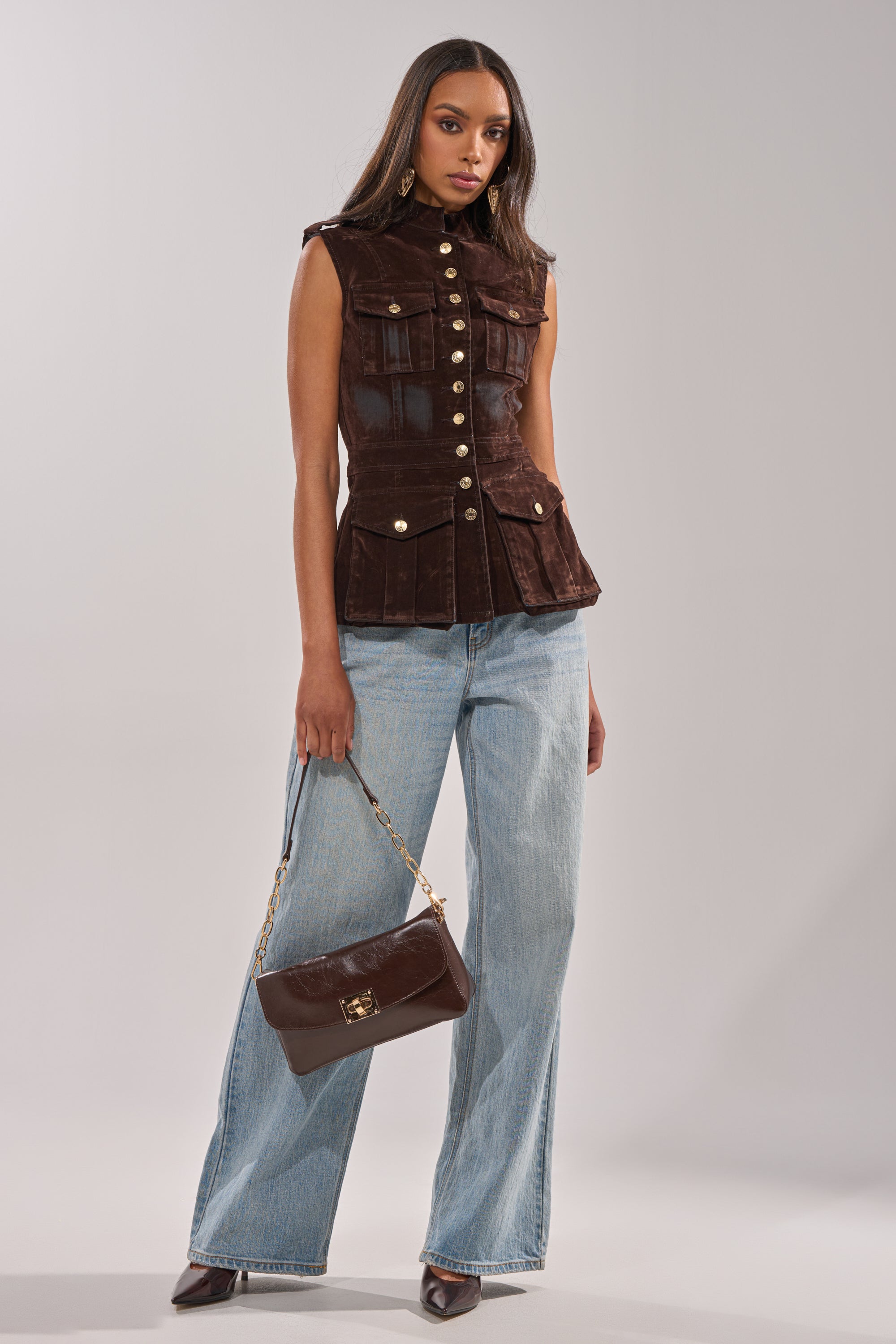 A woman poses in the BACK WITH IT VELVET BUTTON DOWN, paired with light blue wide-leg jeans, brown pointed-toe heels, and a matching brown handbag featuring a gold chain strap.