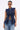 She wears the UMI STRETCH DENIM TOP with multiple pockets and gold hardware, paired with light blue jeans. Slicked-back hair and narrow sunglasses complete her distinct utility-chic look.