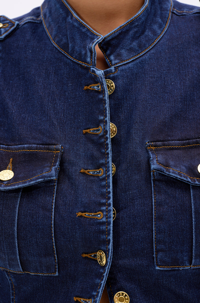 Close-up of the UMI STRETCH DENIM TOP in blue, featuring gold buttons, two flap front pockets, visible seam details, and a high collar. The denim top is partially buttoned for a chic utility look.