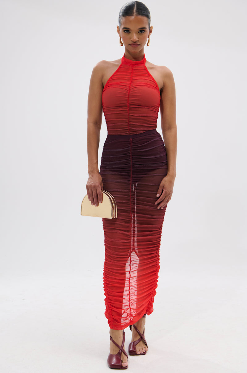 A woman wears the OH FIRE OMBRE MESH BODYSUIT, styled with a small gold clutch and strappy maroon heels, standing against a plain white background.