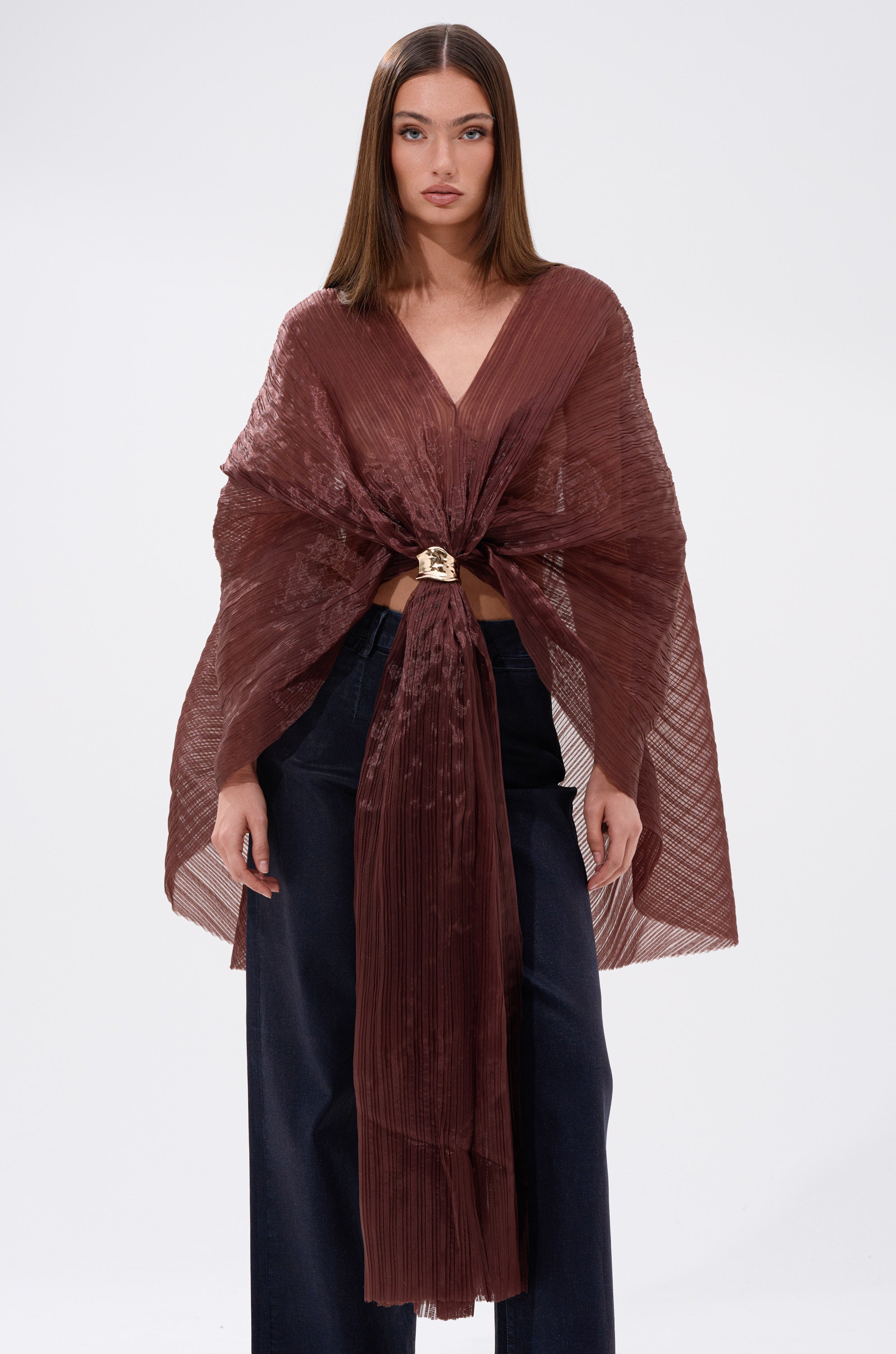 A woman wearing a brown cape over the FLY AWAY WITH ME BLOUSE IN BRONZE, featuring elegant batwing sleeves.