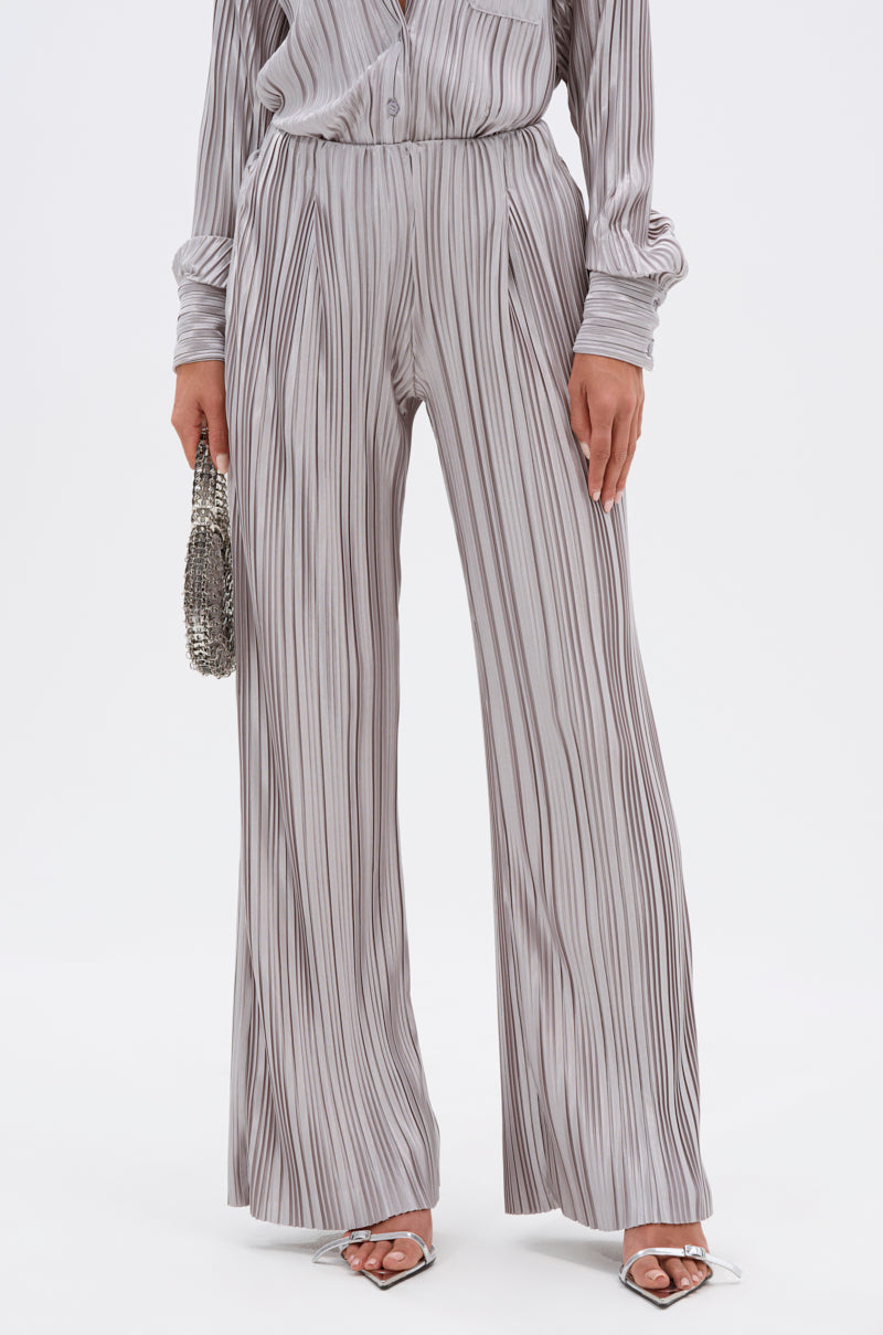Wearing the ALIA SLINKY PALAZZO PANT, a matching gray vertical striped button-up shirt, silver beaded clutch, and silver heeled sandals. 2