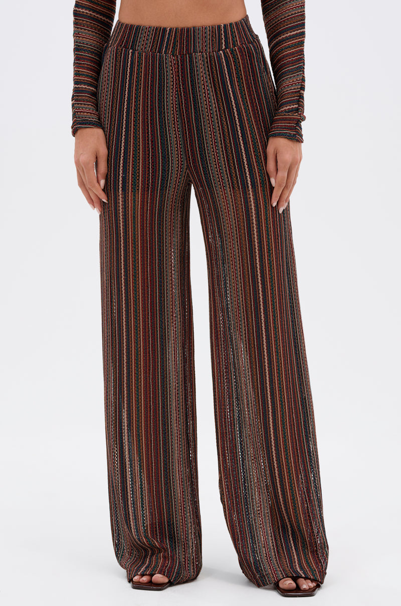 Someone wears the CANDICE STRIPE WIDE LEG PANT, a flowy, relaxed-fit boho-chic pant with brown, black, and red vertical stripes, paired with a matching long-sleeve top for a coordinated outfit. 1
