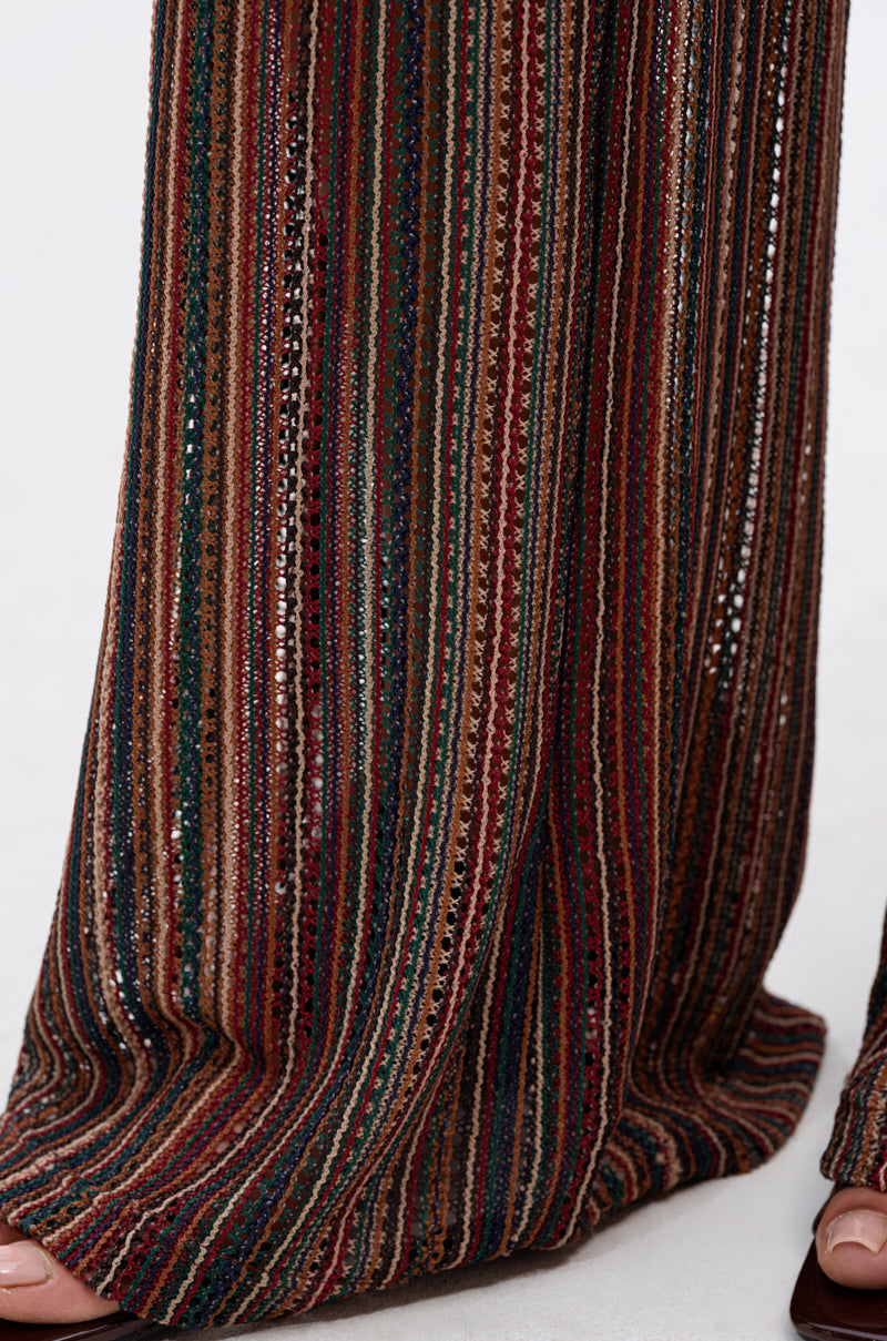 Close-up of the CANDICE STRIPE WIDE LEG PANT, crafted from textured multicolored striped fabric with vertical red, green, beige, and brown lines plus openwork details. The wide-leg pants drape elegantly to the floor. 5
