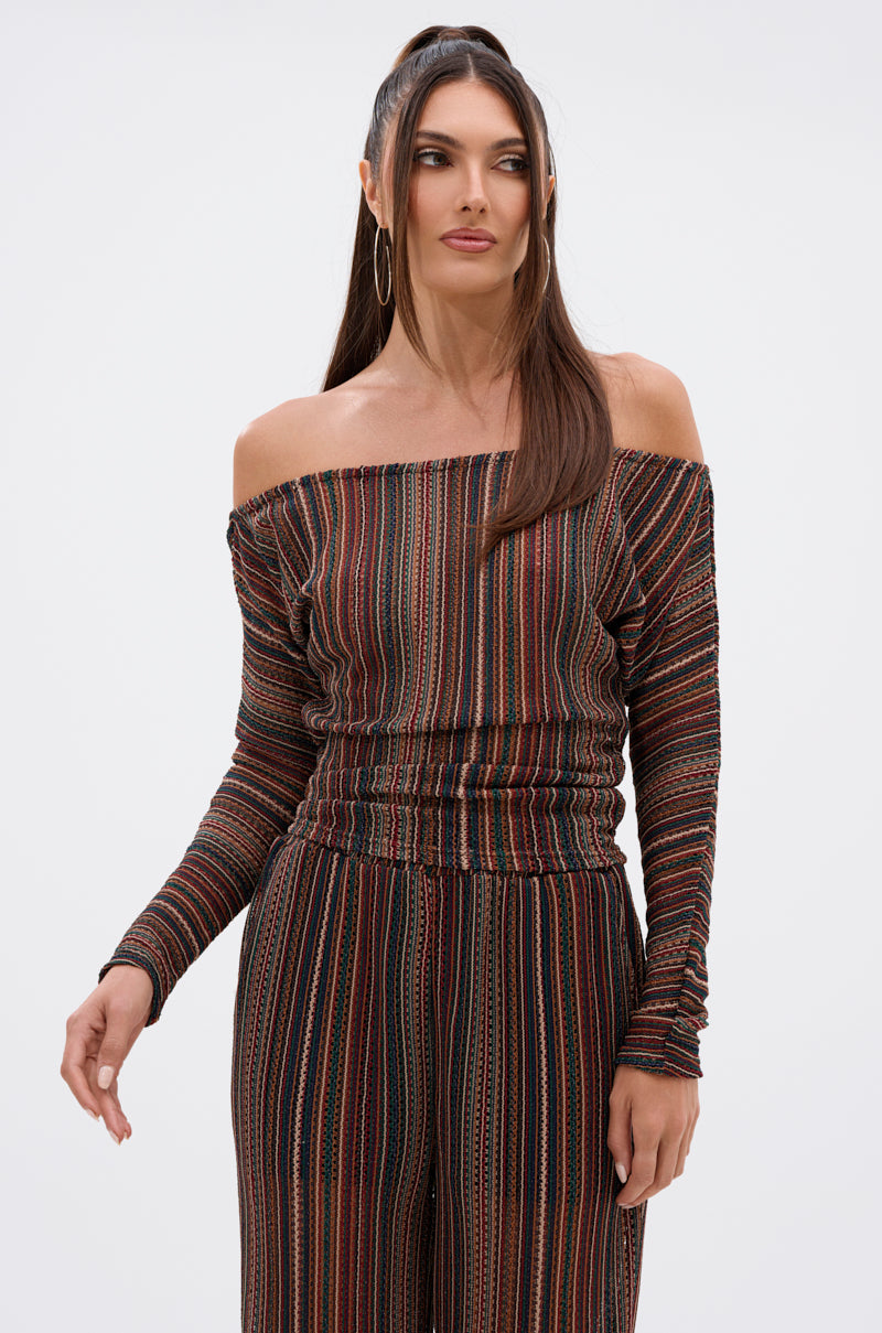 A woman models the CANDICE STRIPE OFF THE SHOULDER BLOUSE against a plain white background, looking slightly to the side with one arm relaxed. 1