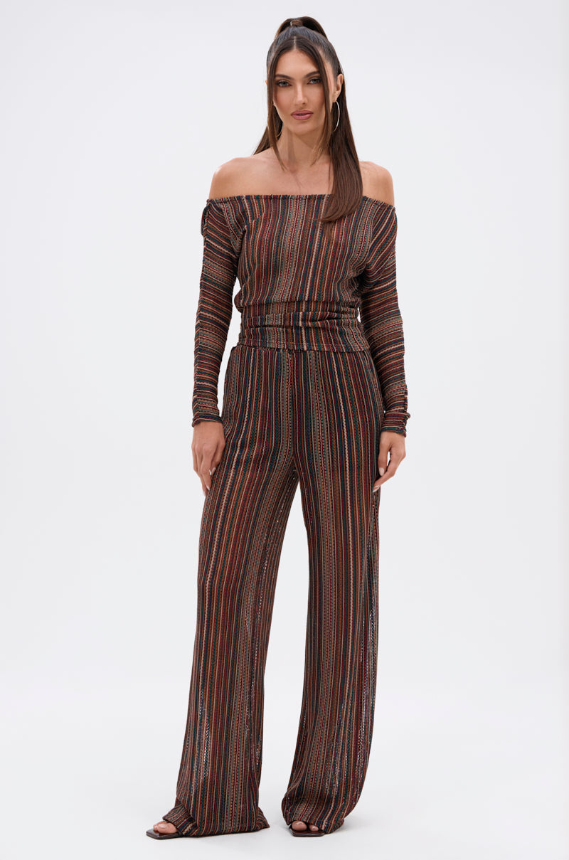 A woman stands against a plain background wearing the CANDICE STRIPE OFF THE SHOULDER BLOUSE and matching striped wide-leg pants. Her long hair is straight and she faces forward with a neutral expression. 4